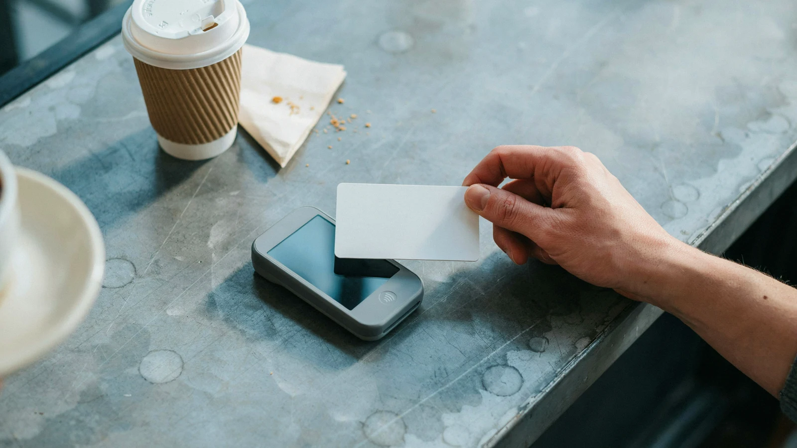 Contactless card tapped on a café terminal, the split-second AI fraud detection check at checkout