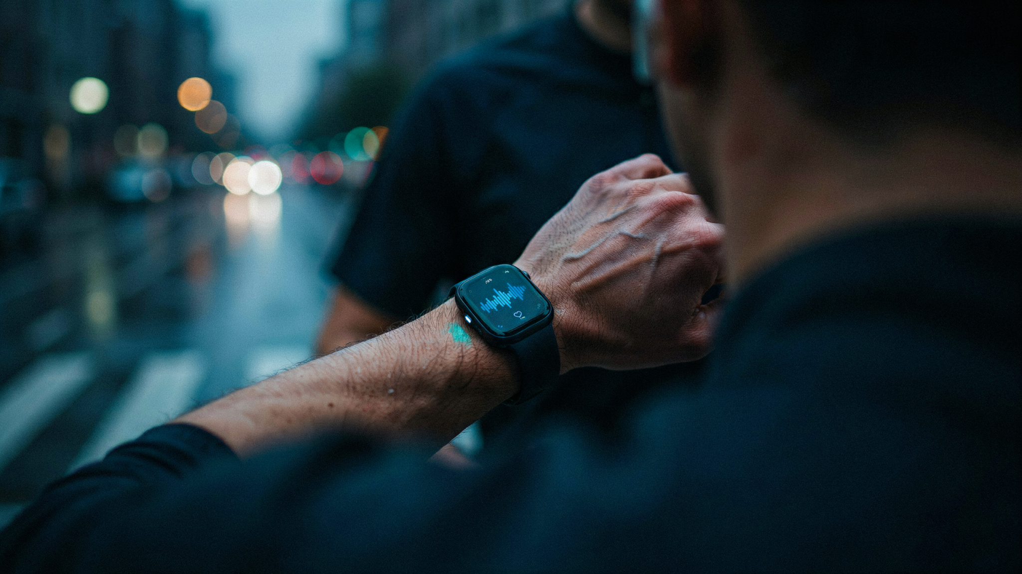 A runner checking voice-coaching audio on an Apple Watch during a city workout at dusk.