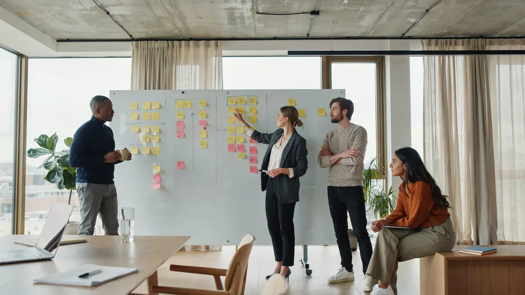 A product team planning a social media app at a sticky-note board during a workshop.