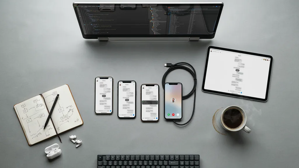 A developer workspace with code on a monitor and a messaging app tested across several phones and a tablet.