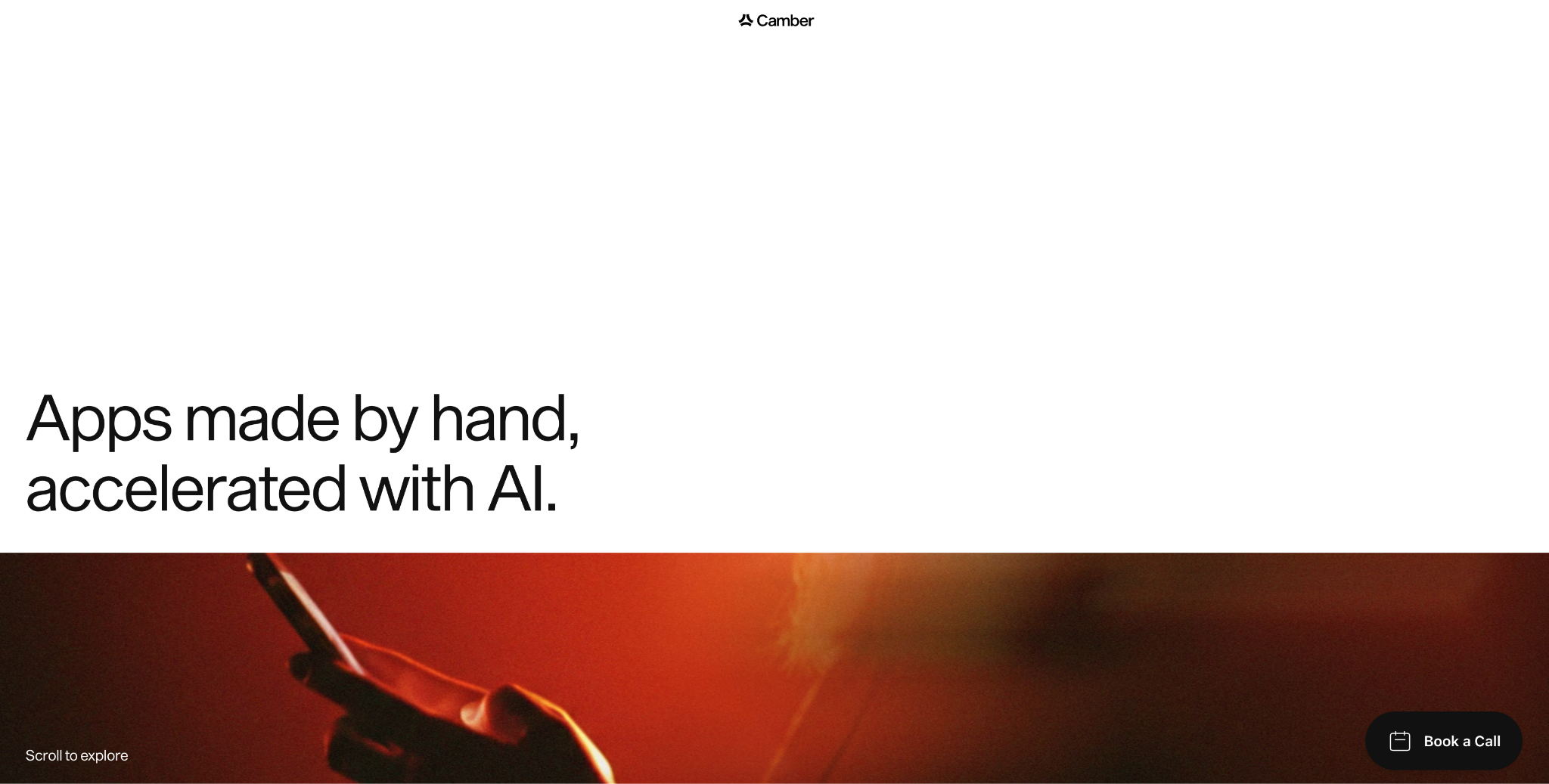 Camber website homepage with the headline "Apps made by hand, accelerated with AI" above a red-lit photo of a hand holding a phone.